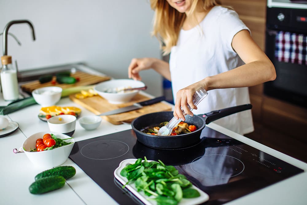 A woman cooking migraine-friendly foods at a stove