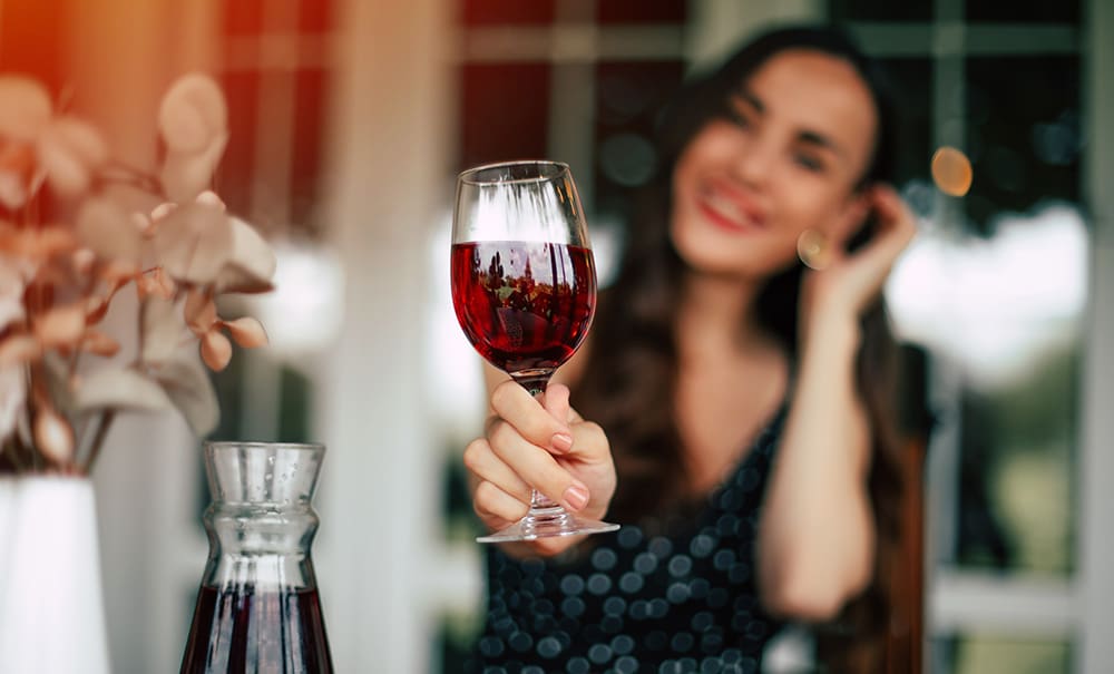 Woman drinking wine chatting about why alcohol gives me a headache